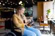 Happy plus size caucasian casual businesswoman in wheelchair using tablet in office