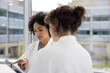 © ReeldealHD images - Two female doctors discussing patient treatment in a busy hospital using a digital tablet