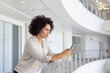 © ReeldealHD images - African American businesswoman holding a smartphone in modern corporate office atrium