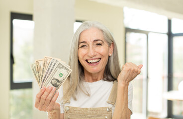 Wall Mural - pretty senior woman looking angry, annoyed and frustrated. with dollar banknotes