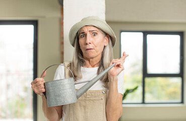 Wall Mural - pretty senior woman crossing fingers and hoping for good luck. gardener concept