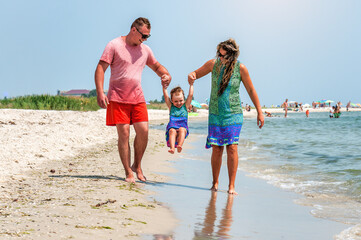 Wall Mural - Young family on the beach under the sun