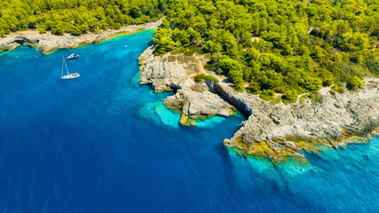 Wall Mural - aerial view on sail yacht, rocks and forest. view from the air on the waves and rocks. sea relaxatio