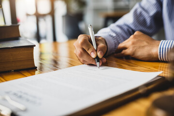 Lawyer working in a law office reading agreement contract documents and signing, Sign the auction documents.