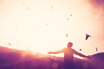 Poster - Freedom feel good and travel adventure concept. Copy space of silhouette man rising hands on sunset sky double exposure colorful bokeh and bird fly background. Vintage tone filter color style.