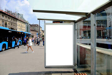 bus shelter with blank ad panel. billboard display. empty white lightbox sign at bus stop. billboard mockup. glass structure. city transit station. urban street. park setting. outdoor advertising.