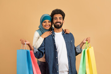 Poster - Happy Customers. Muslim Couple With Shopping Bags Posing Over Beige Studio Background