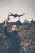 © lightpoet - Young man with a drone outdoors, flying in windy conditions