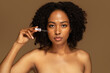 © Prostock-studio - Beautiful young african woman applying serum for glowing skin