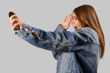 Scared young woman with pepper spray for self-defence on grey background