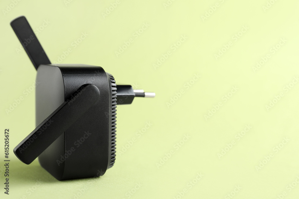 Black WiFi repeater on green background