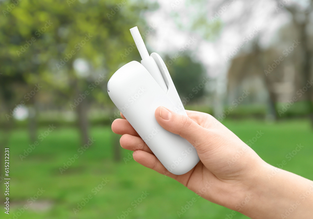 Female hand holding modern electronic cigar outdoors