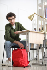 Canvas Print - Male student with backpack sitting at table in library