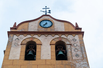 Picturesque bell tower with two bells, against gray sky.