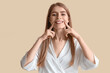 © Pixel-Shot - Young woman doing face building exercise on beige background