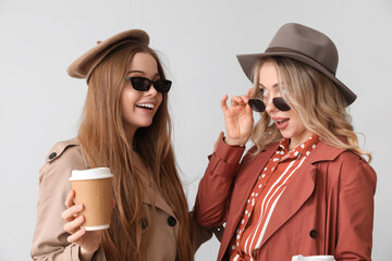 Canvas Print - Young sisters with cups of coffee on light background