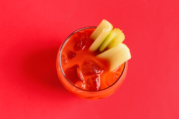 Glass of bloody mary with celery on red background