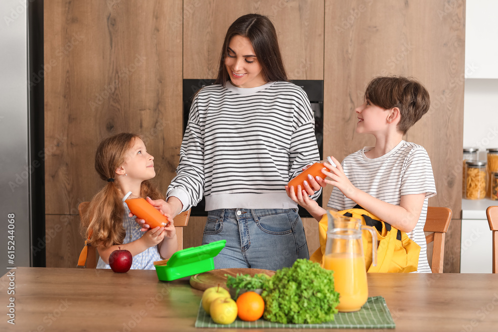 Mother packing school lunch for her little children in kitchen