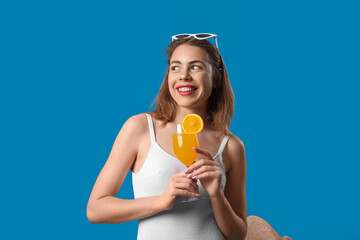 Poster - Young woman in swimsuit with cocktail on blue background