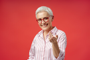 Wall Mural - Portrait of smiling gray haired senior woman wearing stylish eyeglasses flirting camera