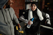 © Seventyfour - Happy young Muslim woman with bottle of water looking at African American male boxing trainer in grey activewear during break