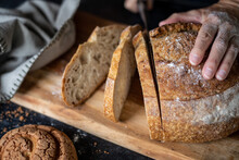 person slicing a loaf of bread on a board, close up, focus on the slice of bread