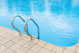 Fototapeta  - Swimming pool with selective focus on metal stairs and copy space for text.