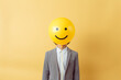 Man with yellow happy emoticon balloon covering face