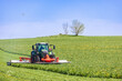 Tractor with a grass mower on a field on a summer day