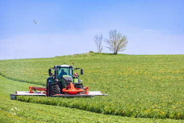 Poster - Tractor with a grass mower on a field on a summer day