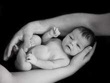 Black And White Photo Of Newborn Baby Being Held By Parents