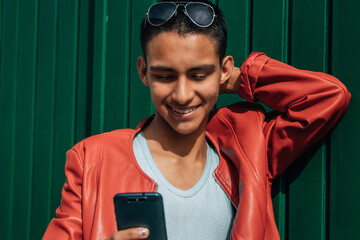 Canvas Print - young hispanic man looking at phone on wall