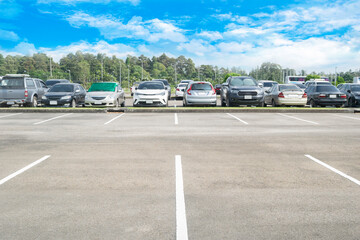 Wall Mural - Wide empty asphalt parking lot background. with many cars parked background. outdoor empty space parking lot with trees and cloudy sky. outside parking lot in a park