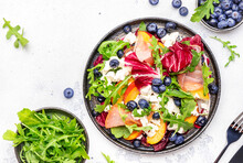 Gourmet Fresh Salad With Arugula, Radicchio, Sweet Peaches, Ham, Cheese And Blueberries. White Table Background, Top View