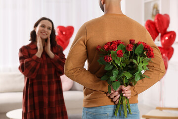 Canvas Print - Man hiding bouquet of red roses for his beloved woman at home. Valentine's day celebration