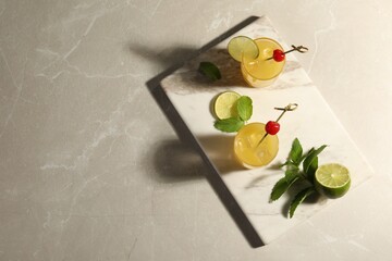 Wall Mural - Glasses of tasty pineapple cocktail decorated with cherry and lime on light grey marble table, top view. Space for text