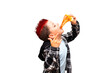 A cute stylish baby boy with a red mohawk on his head is biting a big juicy piece of triangle sausage pizza near his open mouth and showing a rock and roll hand sign.