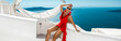 Elegant sexy woman in red swimsuit and silk fluttering pareo is sensually posing on the background of the view of the island of Santorini.