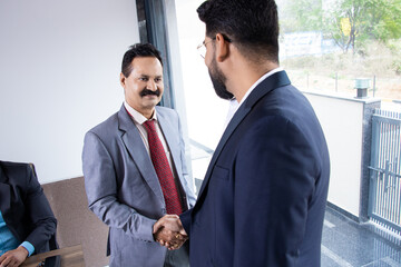 Wall Mural - Indian business people handshaking after finishing up a meeting and striking a deal in boardroom.