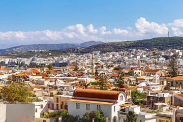 View of resort Greek architecture Rethymno city-port, built by Venetians, from height of Fortezza Castle - fortress on hill Paleokastro. Red tiled roofs and mountains in background. Crete, Greece