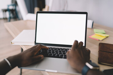 Crop African American man typing on computer at home