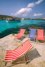 Cruise Boat Sails By A Mediterranean Shoreline With Deck Chairs; Comino Island, Malta