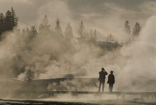 Tourists In Geothermal Steam And Fog Near The Upper Geyser Basin, Yellowstone National Park, USA; Wyoming, United States Of America