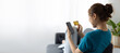 Cheerful Asian young woman lifestyle while sitting on sofa at home using mobile phone and having fun. Woman holding credit card and shopping online.