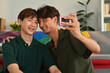 © saltdium - Asian teens gay couple look at digital cameras and take a selfie together, LGBT lifestyle concept.