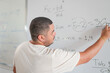 Brazilian teacher explaining a math problem on the blackboard during class in an adult course in Brazil