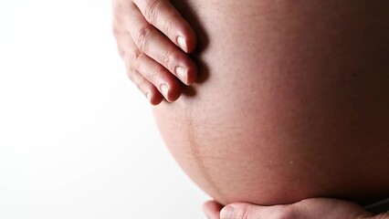 Wall Mural - Closeup of naked round belly caressed by hands of pregnant mother white cloths. Last month of pregnancy - week 36. Side angle view. White background.