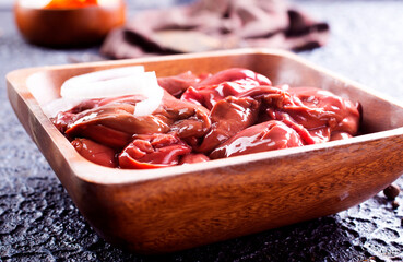 Raw liver with onion in wooden bowl