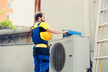 Qualified technician contracted to fix outdoor air conditioner starting job shift. Proficient engineer wearing protective gear preparing to fix damaged external hvac system