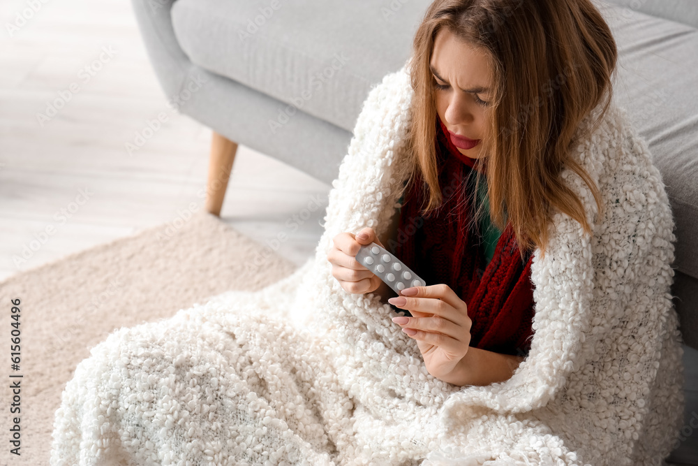 Ill young woman with pills at home